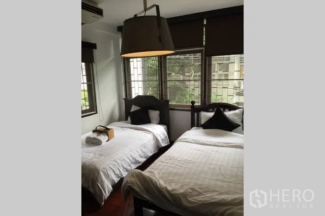Detached House for rent in Watthana, Bangkok - Bedroom with two single beds, large windows and pendant light.