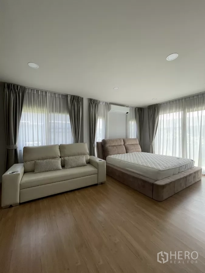 独立式住宅 出租在Bang Phli, Samut Prakan - 宽敞主卧，大面积落窗，软包床与米色沙发。