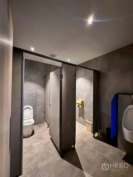 Warehouse for rent in Prawet, Bangkok - Modern warehouse restroom with stalls, urinal, and tiled walls.