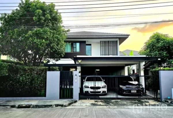 Detached House for rent in Bang Phli, Samut Prakan - Modern two-storey detached house with gated two-car carport and mature trees at sunset