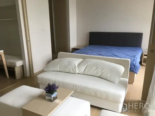 公寓 出租或出售在Watthana, Bangkok - 采光充足的一居室，设有沙发休闲角、双人床与浅色木地板