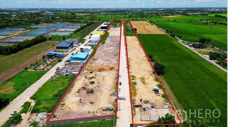 ที่ดิน ขายในBang Bua Thong, Nonthaburi - ภาพมุมสูงของที่ดินทรงสี่เหลี่ยมผืนผ้ายาว ขีดเส้นสีแดง มีถนนคอนกรีตตรงกลาง ข้างเคียงโกดังและทุ่งนา บางบัวทอง