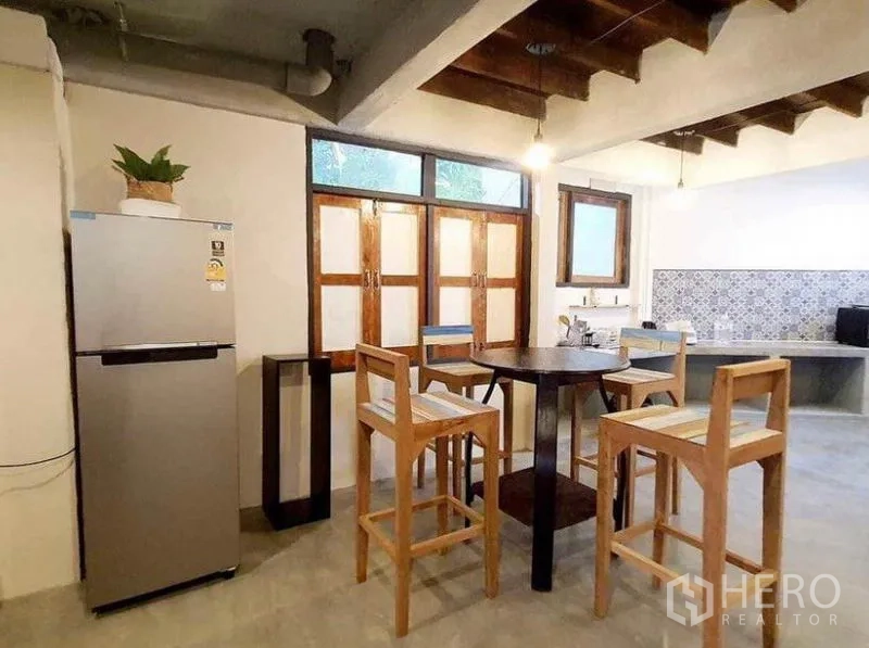 独立式住宅 出租在Pathum Wan, Bangkok - 可用餐厨房，圆桌、高脚木椅、不锈钢冰箱与木窗