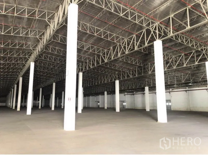 货栈 出租在Lam Luk Ka, Pathum Thani - 内部高净空，隔热金属屋顶与白色柱体结构。