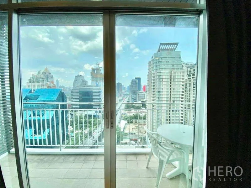 Condominium for rent or sale in Sathon, Bangkok - Balcony with small table overlooking the Sathorn business district skyline.