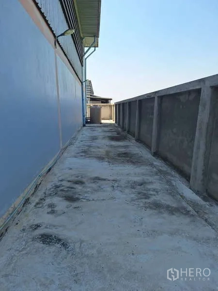 货栈 出售在Pathum Thani - 建筑侧边混凝土服务通道，沿围墙延伸。