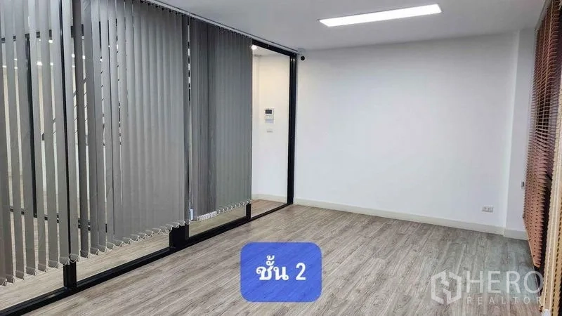 Townhouse for rent in Bueng Kum, Bangkok - Second-floor room with full-height glass partition and vertical blinds over wood-look floors.