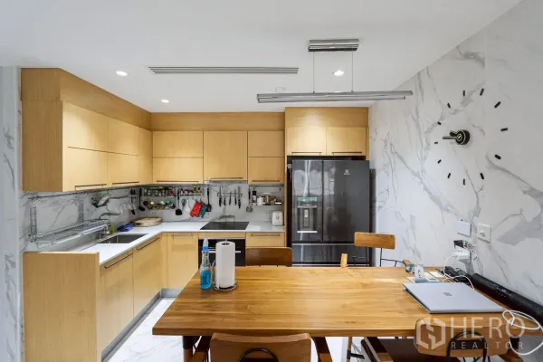 公寓 出租在Pathum Wan, Bangkok - 开放式厨房，浅木橱柜、餐桌和对开门冰箱。