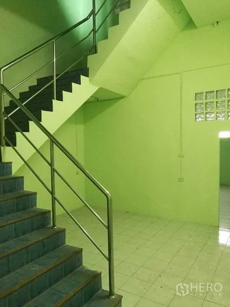 Factory for rent in Mueang Samut Sakhon, Samut Sakhon - Stairwell with stainless steel handrail beside a tiled area inside the factory.