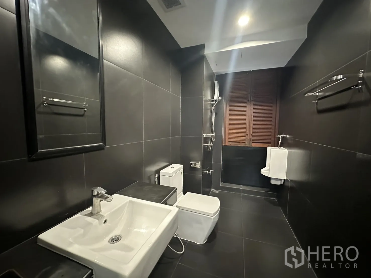 公寓 for rent in Pathum Wan, Bangkok - 深色瓷砖浴室，设洗手台、坐便器、小便斗和淋浴区。