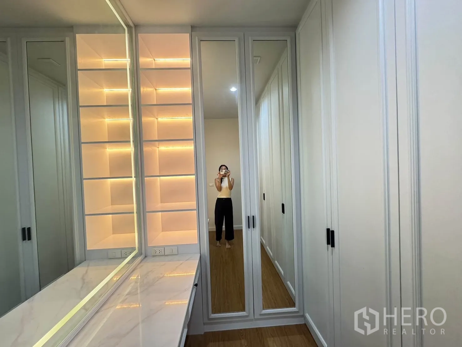 Detached House for rent or sale in Bang Phli, Samut Prakan - Walk-in closet with mirrored wardrobes, illuminated display shelves and a long dressing counter.