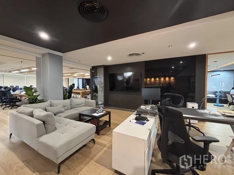 Office Space for rent in Bang Rak, Bangkok - Casual lounge with sectional sofa, TV wall, and desks beside the open office.