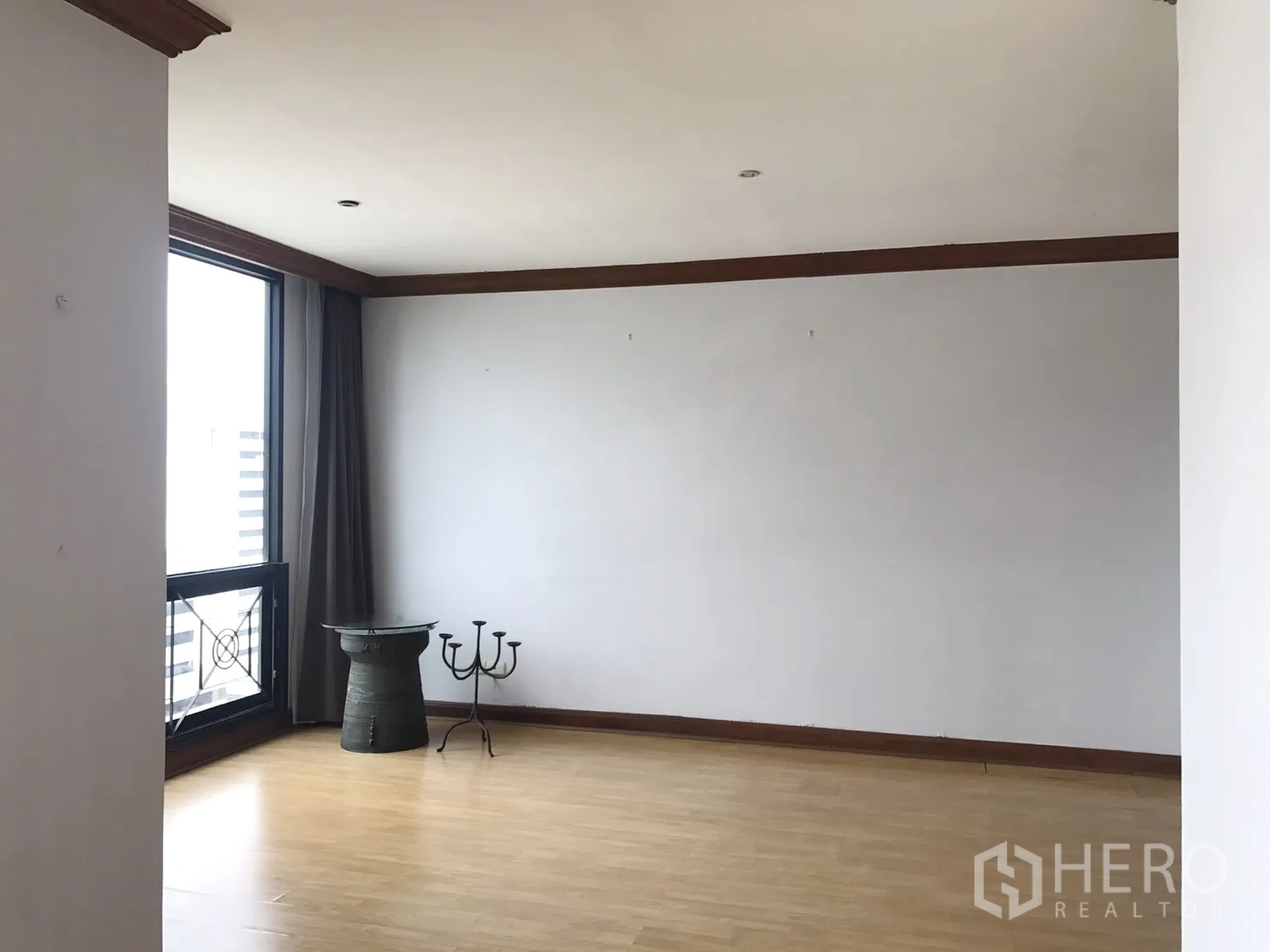 Condominium for rent in Pathum Wan, Bangkok - Empty multipurpose room with wood flooring and a large window overlooking the city.