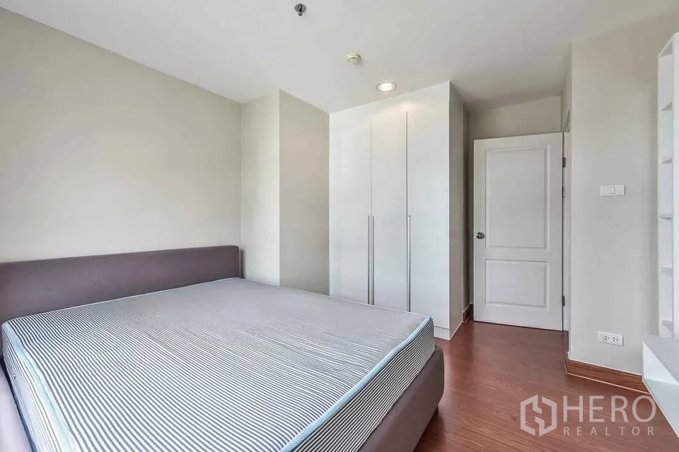 คอนโด for rent in Huai Khwang, Bangkok - ห้องนอนหลักพร้อมเตียงขนาดใหญ่ ตู้เสื้อผ้าบิวท์อิน และผนังโทนอ่อน