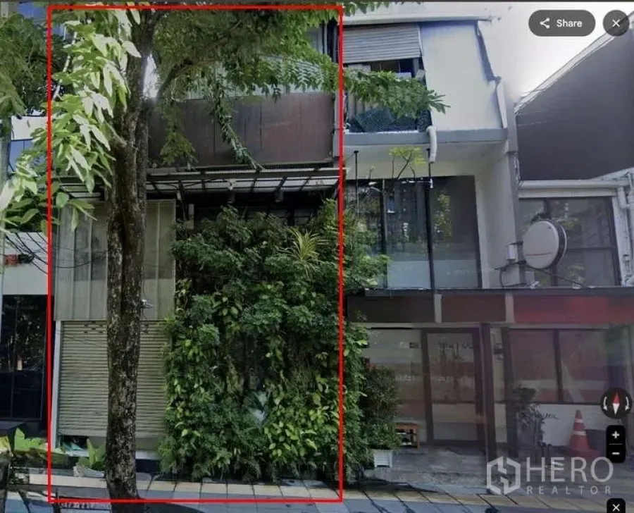 店屋 出租在Pathum Wan, Bangkok - 曼谷三层商铺外立面，整面玻璃门面与卷闸，设有绿植垂直花墙，街道树荫环绕。