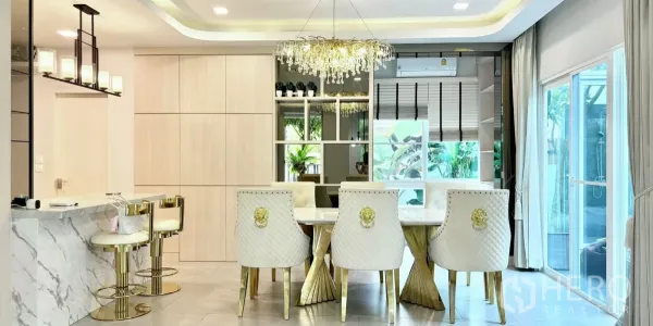 Detached House for rent or sale in Prawet, Bangkok - Stylish dining area with crystal chandelier, white table, gold accents and sliding doors to the patio.