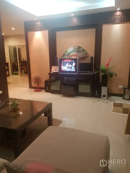 Detached House for sale in Lat Krabang, Bangkok - Cozy living area with sofa, coffee table and media wall with built-in shelves and TV.