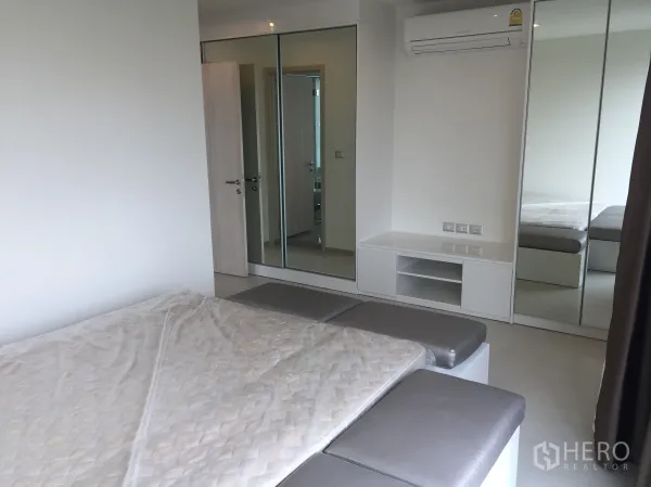 Condominium for rent in Khlong Toei, Bangkok - Primary bedroom with mirrored wardrobes, large bed, built-in storage, and air conditioning.