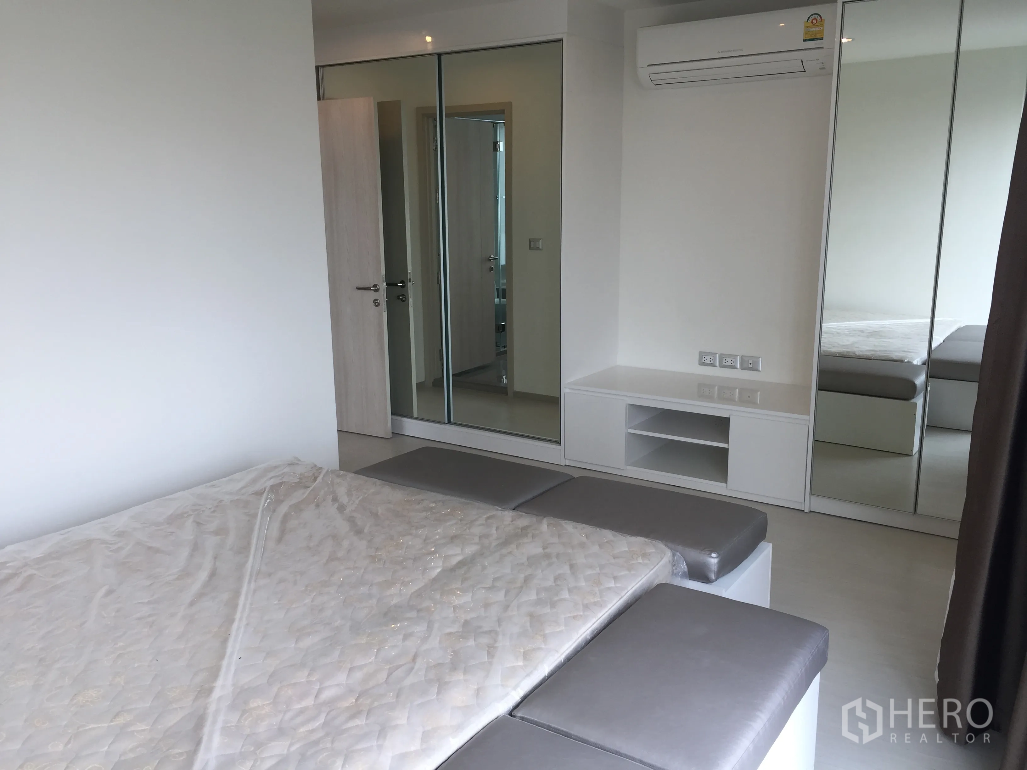 Condominium for rent in Khlong Toei, Bangkok - Primary bedroom with mirrored wardrobes, large bed, built-in storage, and air conditioning.