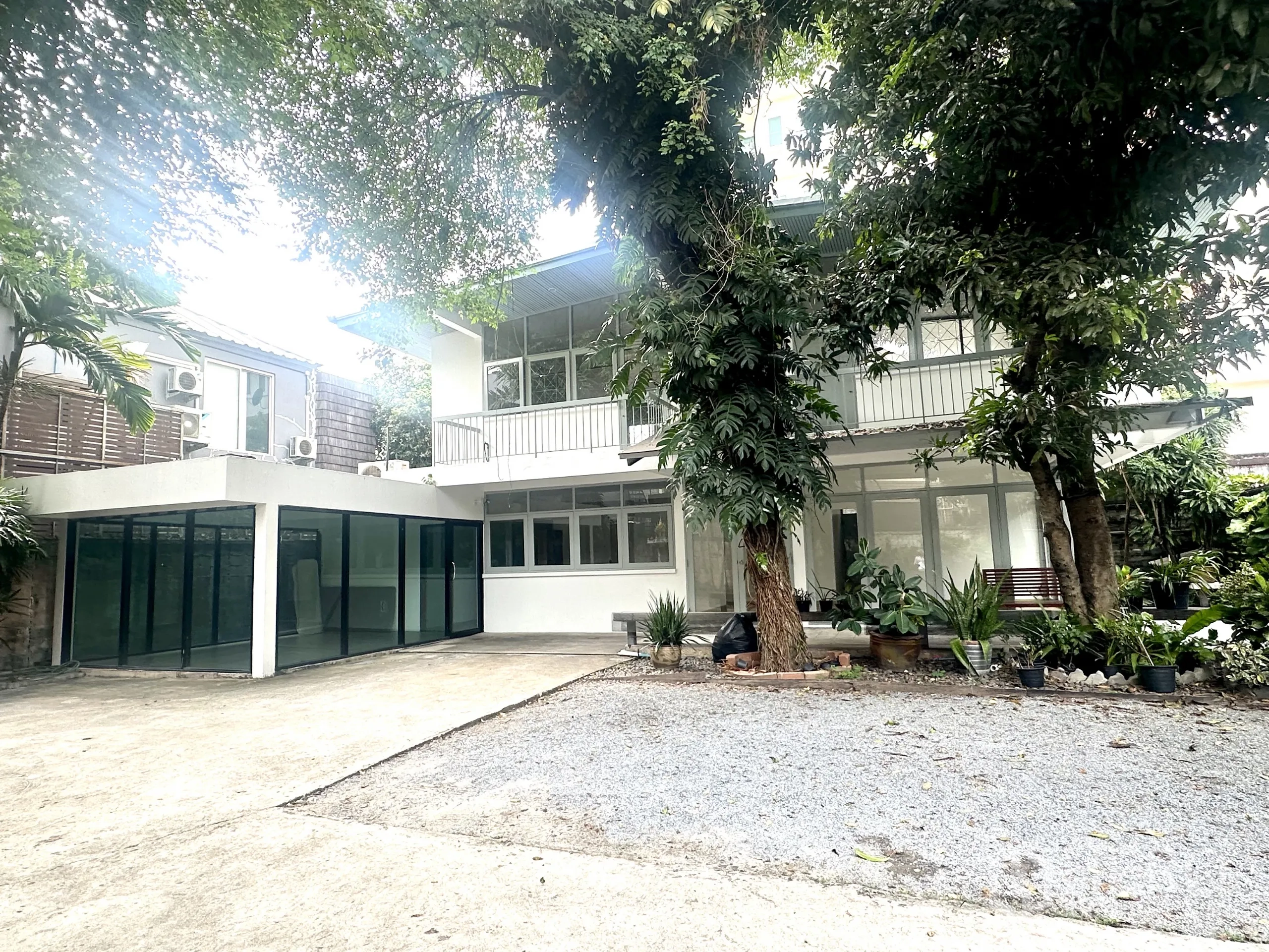独立式住宅 出租在Watthana, Bangkok - 瓦塔那两层白色独立屋，树荫浓密，碎石与混凝土车道，采光充足的窗户。