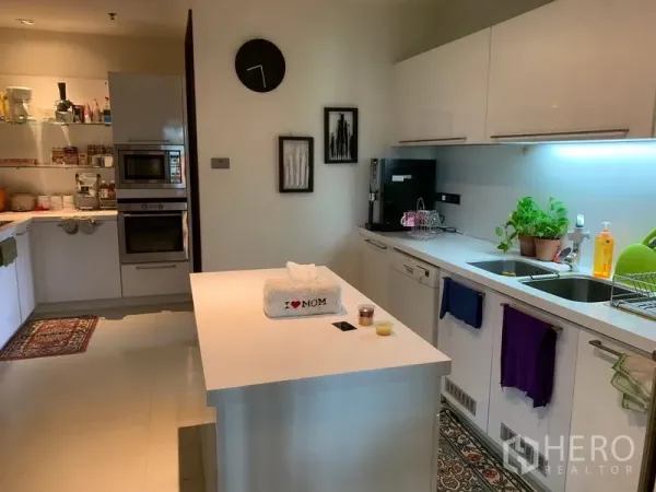 Condominium for sale in Khlong Toei, Bangkok - Modern white kitchen with an island, double ovens and under-cabinet lighting.