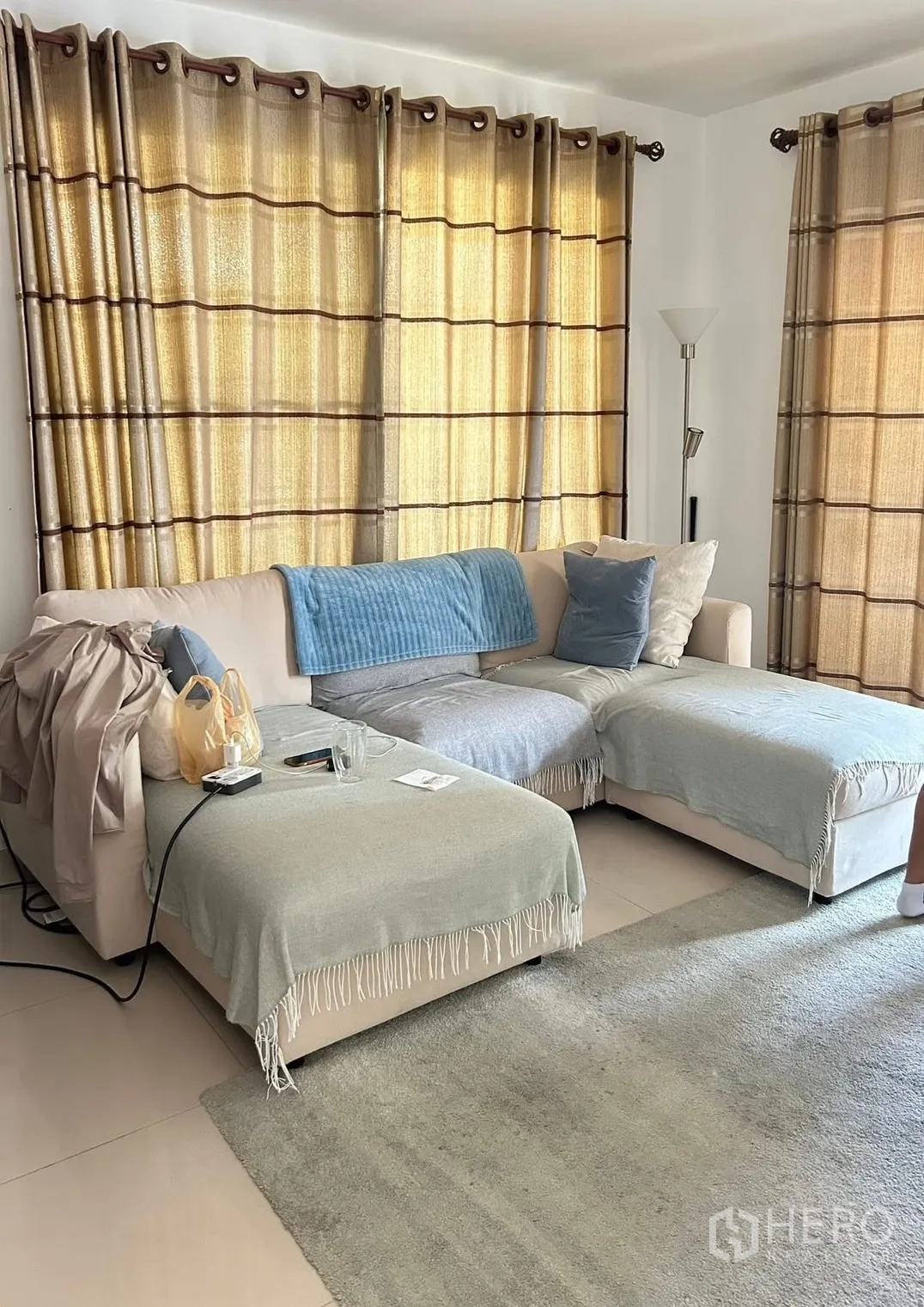 Detached House for rent in Bang Na, Bangkok - Cozy living corner with L-shaped sofa, floor lamp, and full-length curtains.