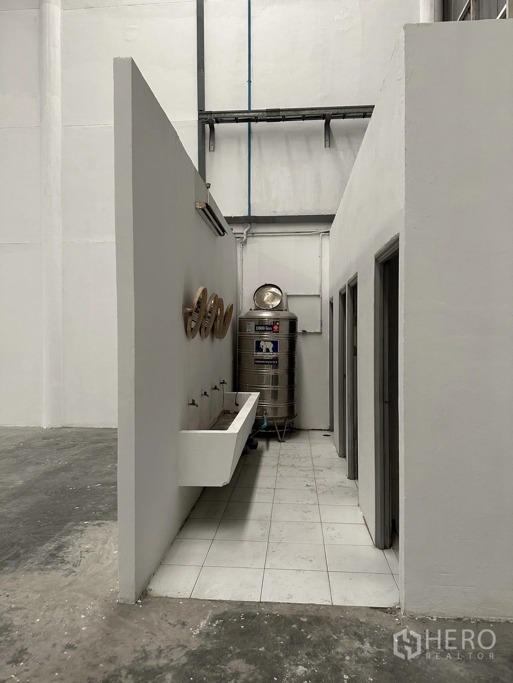 Factory for rent in Khlong Luang, Pathum Thani - Warehouse wash area with long sink, stainless water tank, and doors to restrooms.