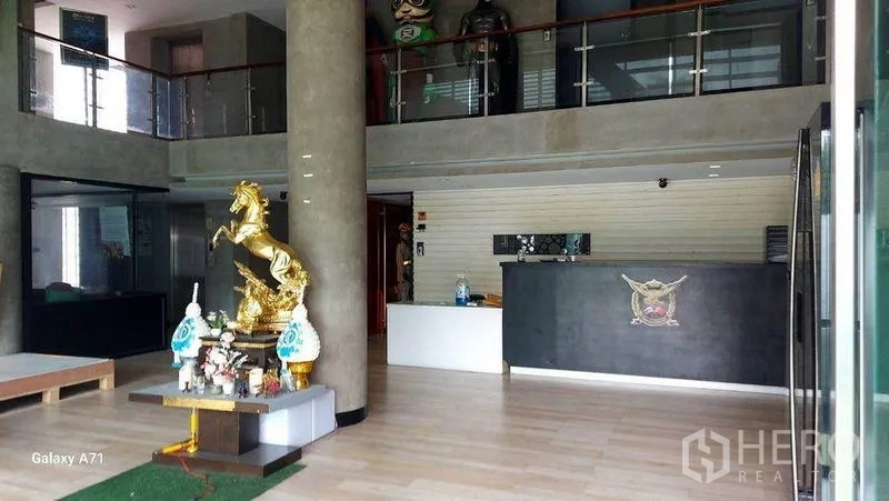 带办公室的家 出租在Nong Khaem, Bangkok - 挑高大堂，设接待台、混凝土柱与玻璃栏杆的夹层。