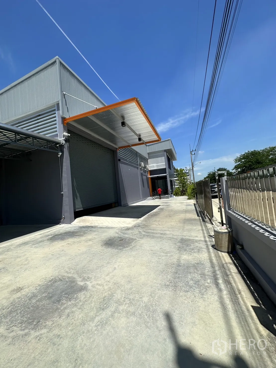 工厂 出售在Lam Luk Ka, Pathum Thani - 正立面带卷闸门与宽阔混凝土前场。
