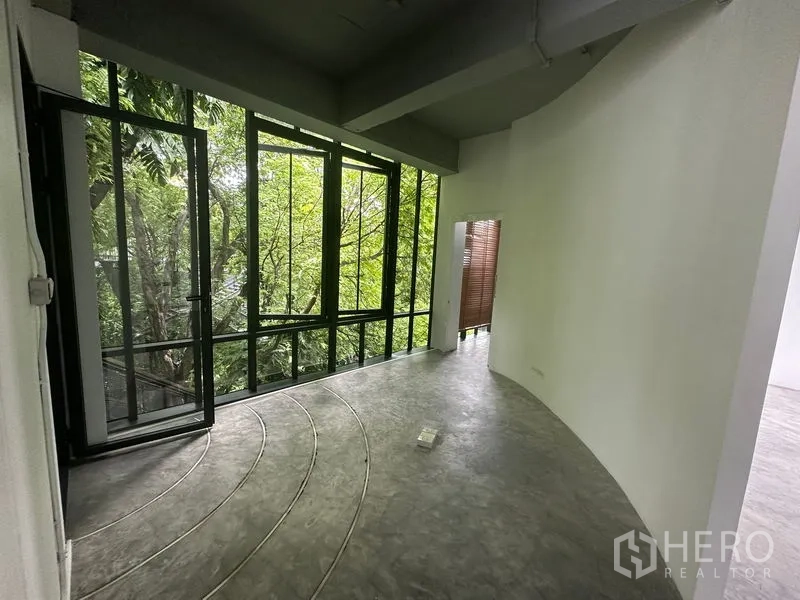 Office Space for rent in Khlong Toei, Bangkok - Curved reception or breakout area with full-height black-framed glass overlooking leafy trees.