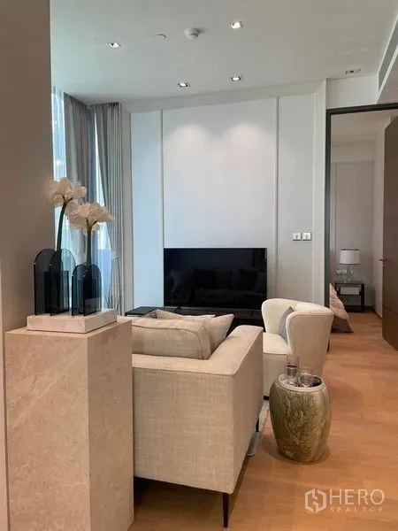 Condominium for rent in Pathum Wan, Bangkok - Cozy lounge with sofa, armchair, TV unit and tall curtains.