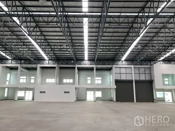 Factory for rent in Phra Nakhon Si Ayutthaya - Spacious warehouse interior with 9‑meter steel roof, skylights and large roller doors.