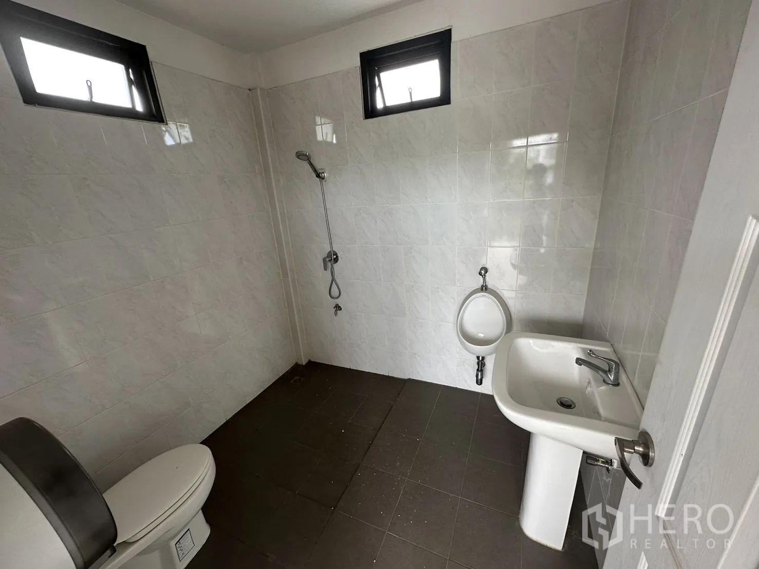 Warehouse for rent in Suan Luang, Bangkok - Clean restroom with toilet, urinal, sink, and shower area.