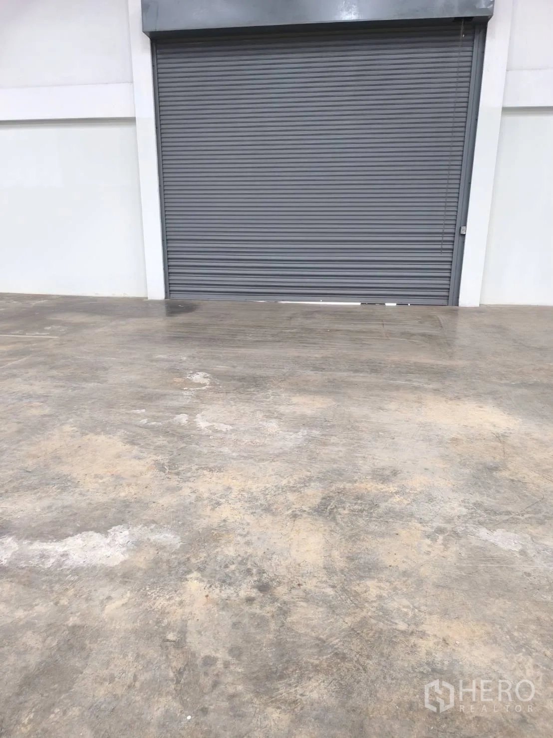 Factory for sale in Khlong Luang, Pathum Thani - Close view of the gray rolling shutter door inside the warehouse.