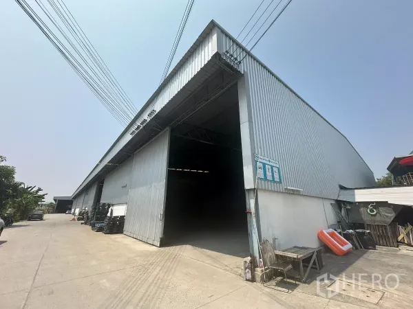 Warehouse for rent in Bang Phli, Samut Prakan - Large metal-clad warehouse exterior with wide sliding door and truck-friendly driveway in Bang Phli.