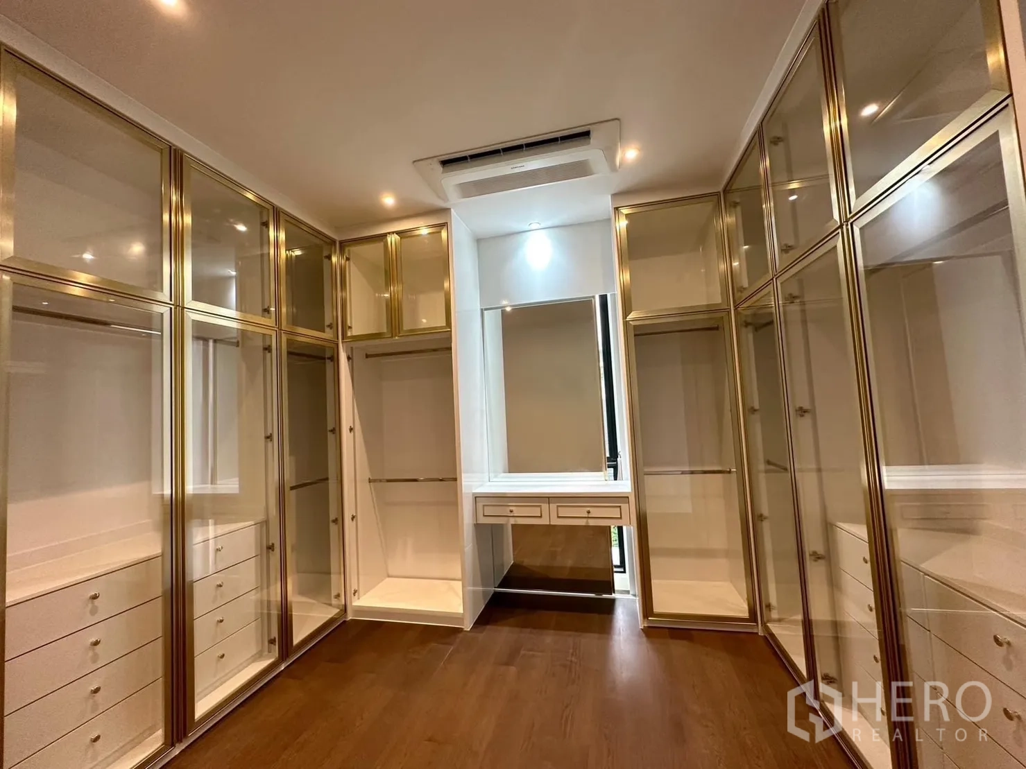 Detached House for rent - Walk-in closet with gold-framed glass wardrobes and dressing table on wood flooring.