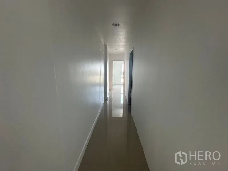 Home Office for rent in Bang Na, Bangkok - Narrow corridor with recessed lighting and shiny tiled floor.