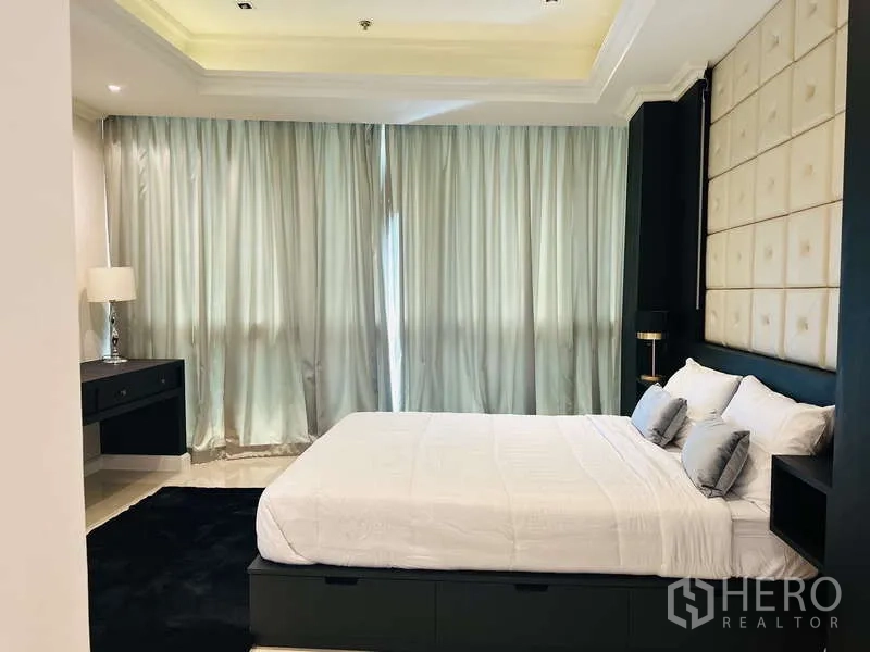 Condominium for rent or sale in Khlong Toei, Bangkok - Cozy bedroom with padded headboard, soft lighting and full drapes for privacy.