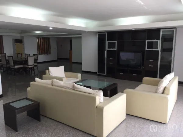 คอนโด ให้เช่าในWatthana, Bangkok - ห้องนั่งเล่นพร้อมชั้นวางทีวีไม้สีเข้ม โซฟาสีครีม และพื้นกระเบื้องเงา