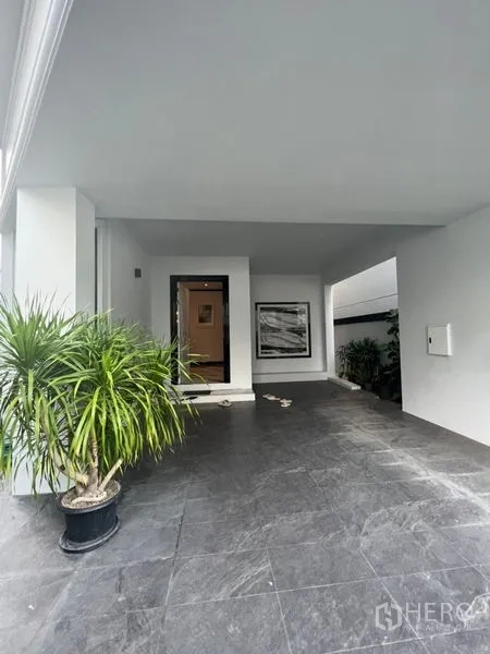 带办公室的家 出租或出售在Watthana, Bangkok - 前方有顶车棚，深色地砖并摆放绿植。