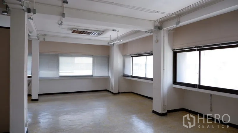 办公空间 出租在Watthana, Bangkok - 转角开放式区域，多面窗与结构柱，吊顶照明完善。