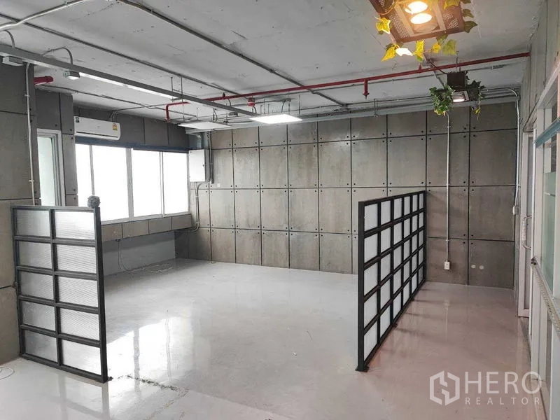 办公空间 出租在Watthana, Bangkok - 办公角落，半透明隔断、混凝土特色墙与吊灯绿植。