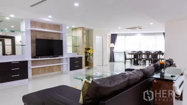 Condominium for rent or sale in Khlong Toei, Bangkok - Spacious living area with TV feature wall, glass shelves and view to dining zone.
