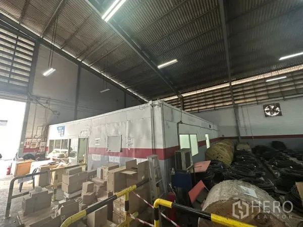 货栈 出租在Khlong Toei, Bangkok - 高挑仓储大厅，内部模块化办公室，安全护栏旁堆放电缆与纸箱。