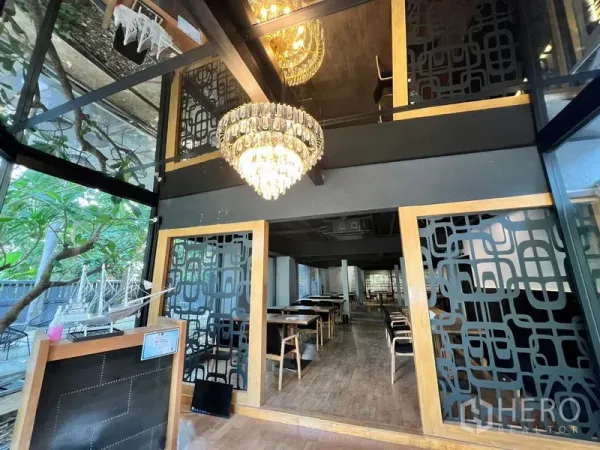 Retail Space for rent in Bangkok - Double-height glass foyer with chandelier and patterned screens leading to a dining area.
