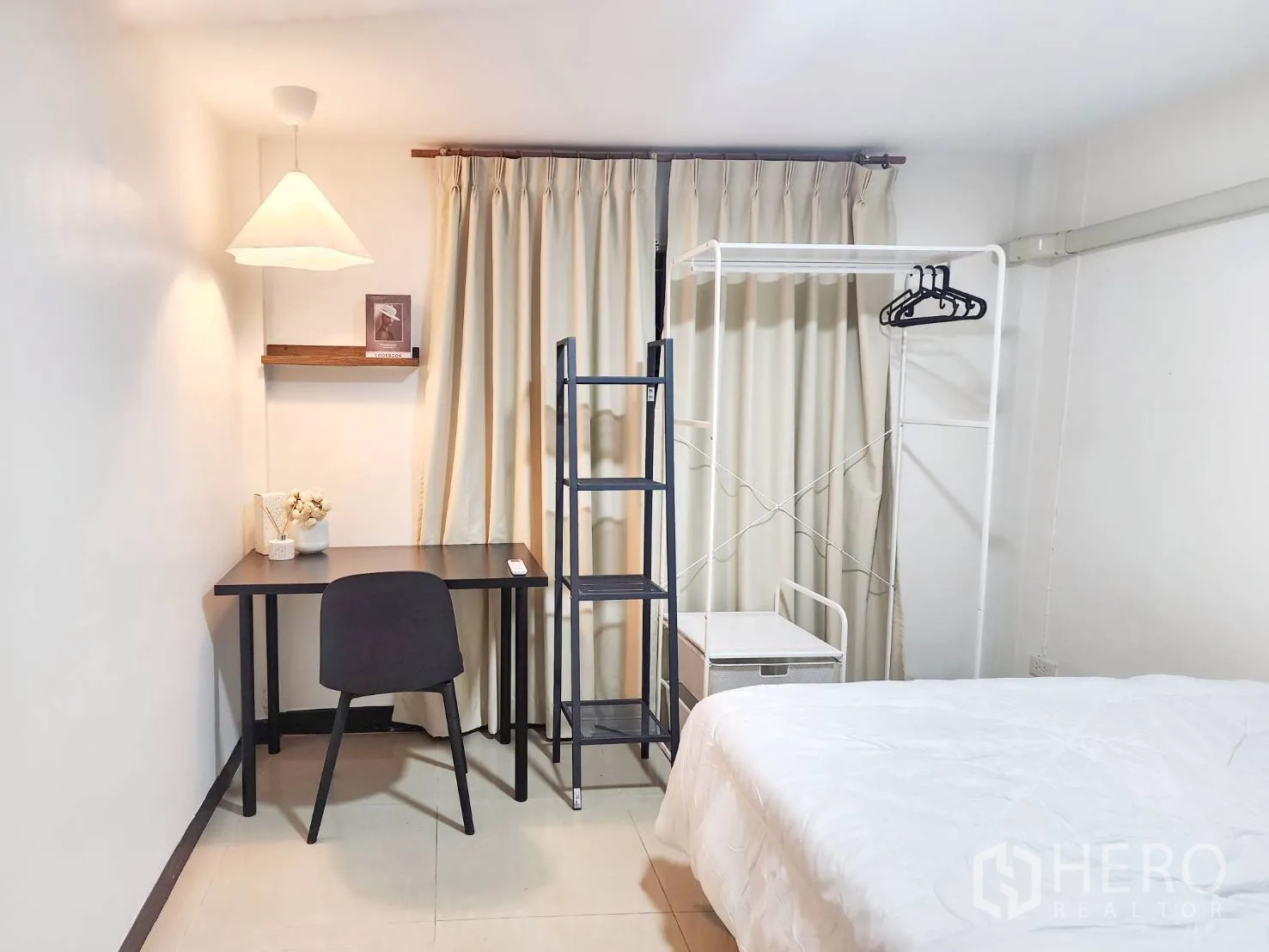 บ้านเดี่ยว for rent in Huai Khwang, Bangkok - ห้องนอนพร้อมโต๊ะทำงาน ชั้นวาง ราวแขวนเสื้อ และแสงไฟนุ่มๆ ข้างผ้าม่าน