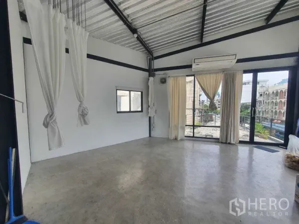Retail Space for rent in Sathon, Bangkok - Corner of the retail space with large windows, balcony access and urban views, featuring an AC unit and tied-back drapes.