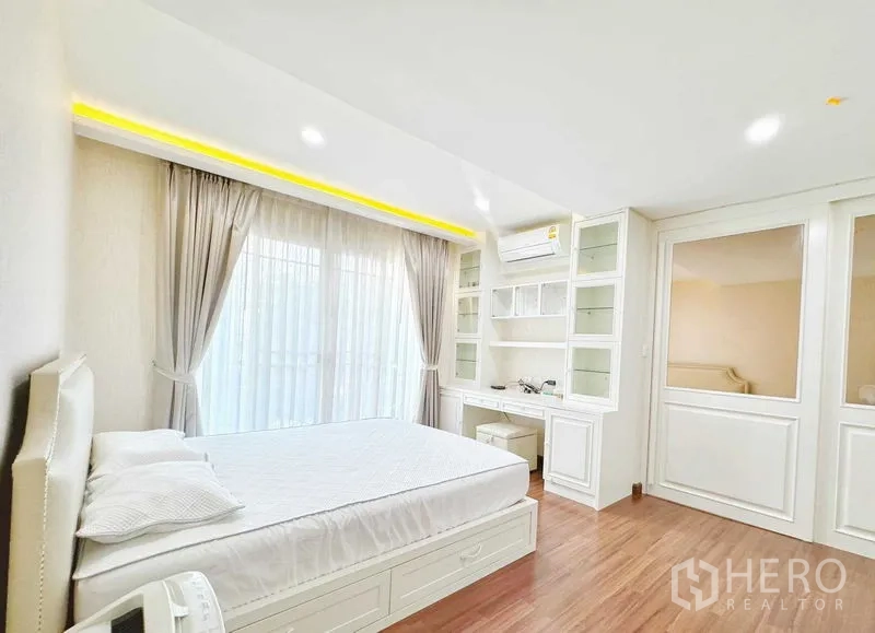 Townhouse for rent in Phra Khanong, Bangkok - Master bedroom with cove lighting, balcony and built-in cabinetry.