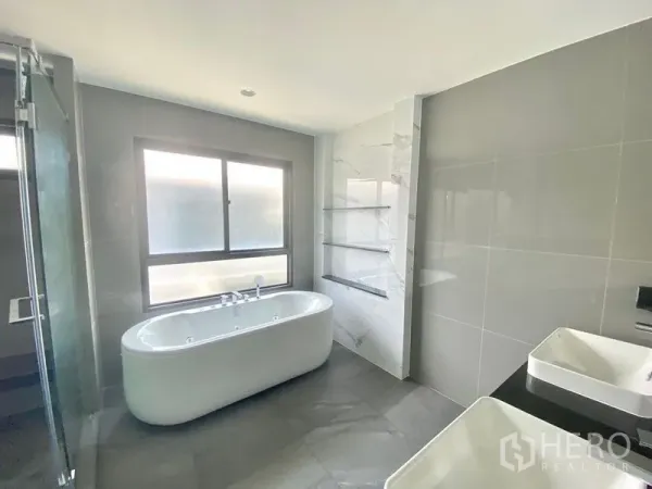 Detached House for sale in Bang Kapi, Bangkok - Spacious bathroom with a freestanding bathtub, double basins and a large frosted window.