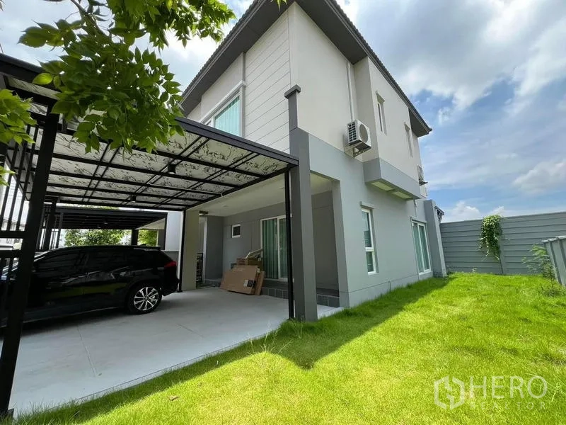 Detached House for rent in Bang Phli, Samut Prakan - Side exterior showing lawn, privacy fence, and double carport beside the house.
